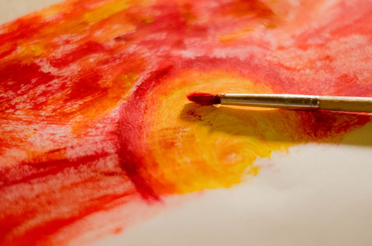 gallery-02 A dynamic abstract painting showcasing vibrant red and yellow hues with a paintbrush.