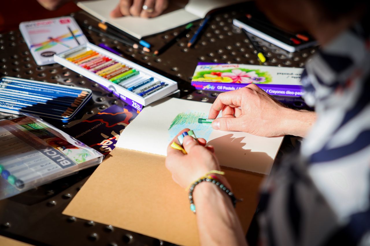 Person drawing with oil pastels in a bright, creative workspace.
