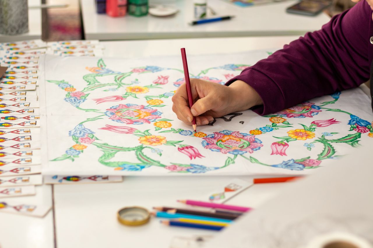 gallery-06 A person coloring a detailed floral design with pencils, showcasing creativity.