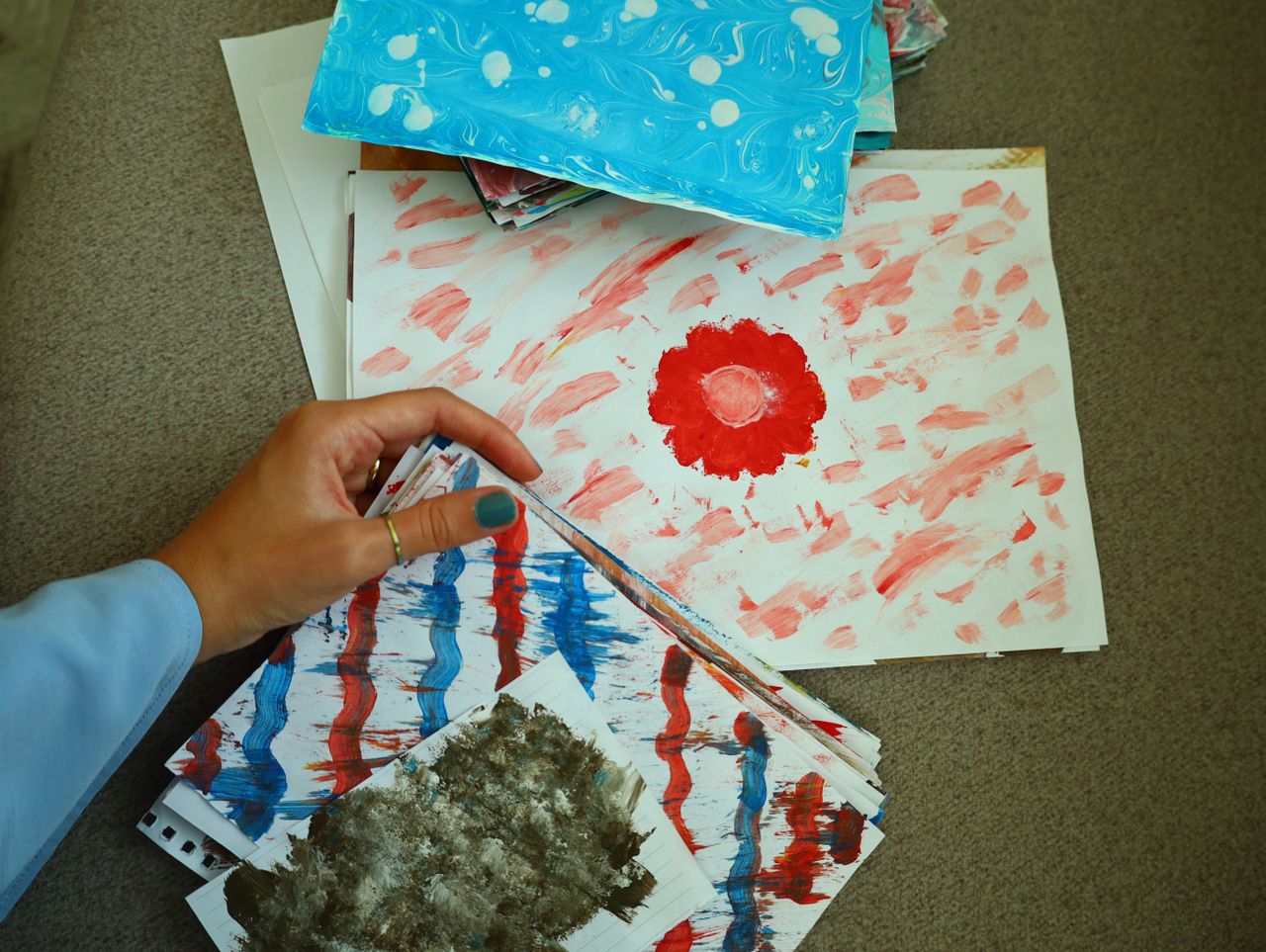 gallery-05 A person organizing vibrant abstract artworks, showcasing creative expression and diverse patterns.