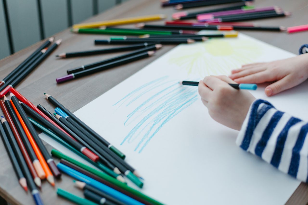 gallery-03 A child drawing with colored pencils on a paper, showcasing creativity and art.
